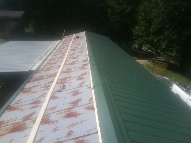 Old rusted panels beside newly installed green metal roofing — Wind Damage Roof Repair by Roofing Brothers in Farnhamville