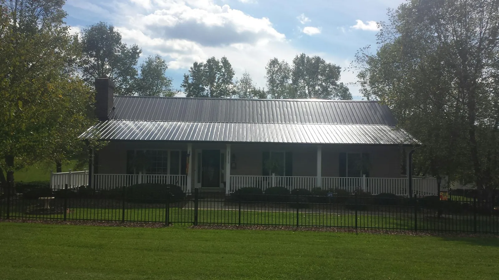 Gray metal roof on a brick ranch with a full width front porch — Gutter Guard Installation work by our crew in Farnhamville