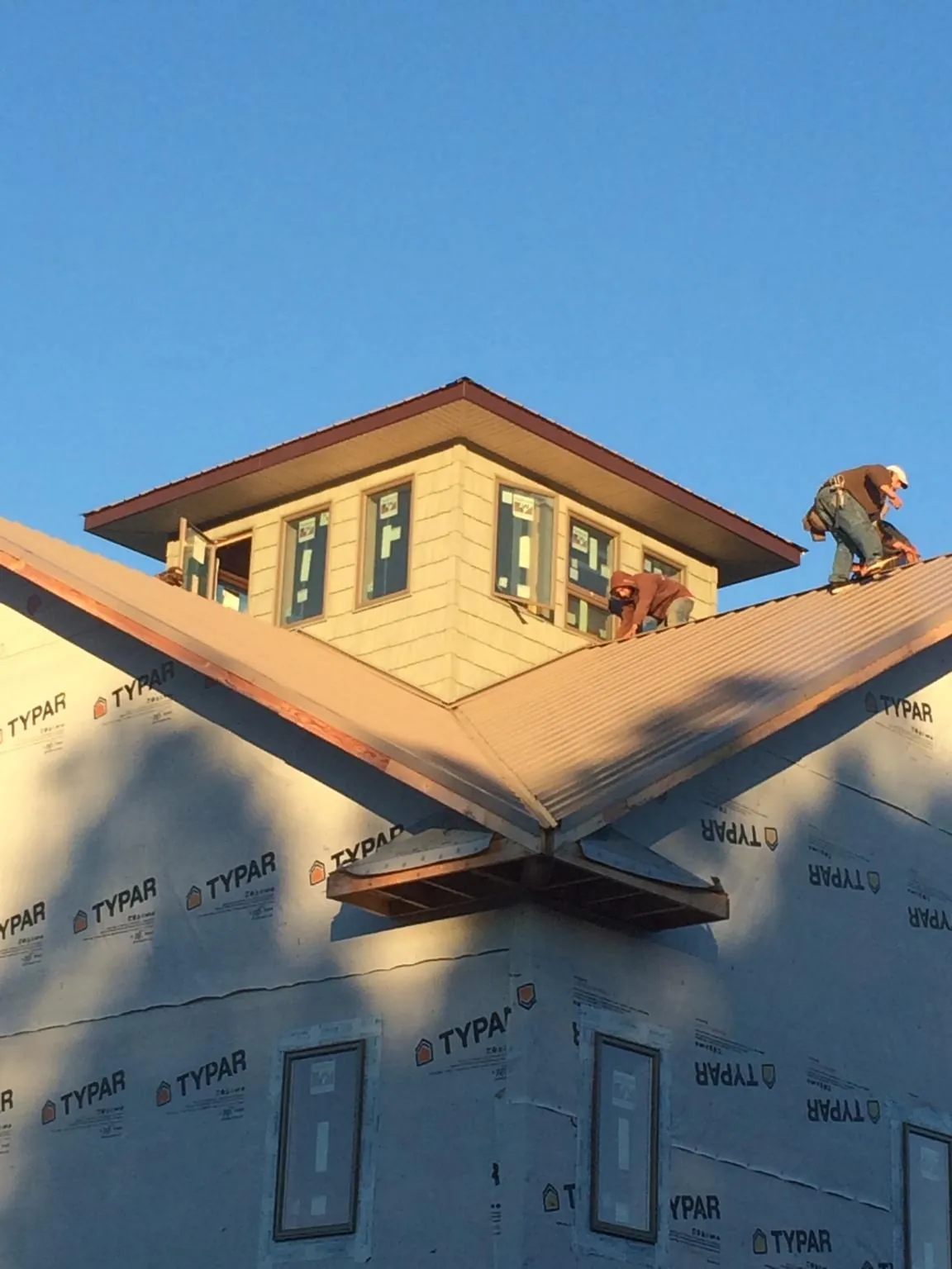 Roofers working around a rooftop cupola on a new metal roof at sunset — Roof Waterproofing in Farnhamville by Roofing Brothers